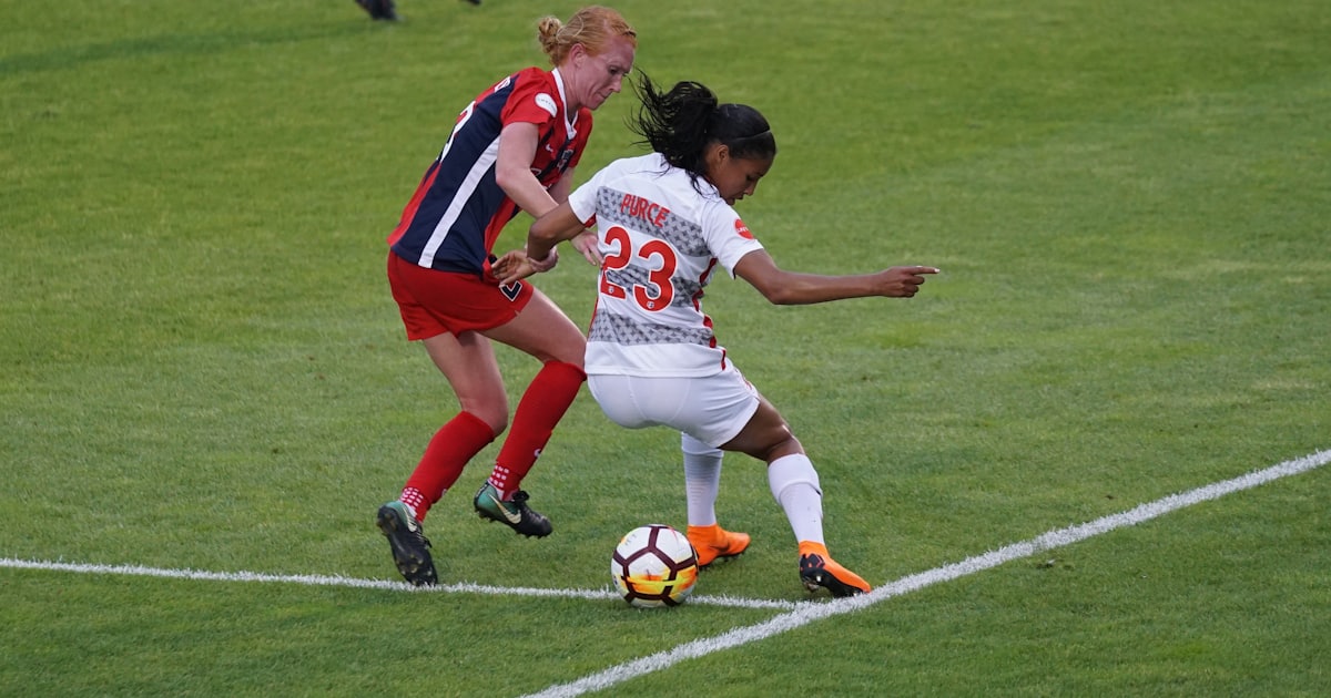 two women playing soccer on field
