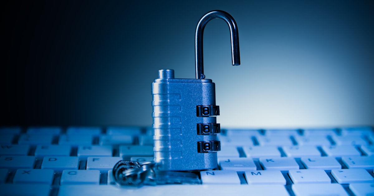 An unlocked padlock rests on a computer keyboard.