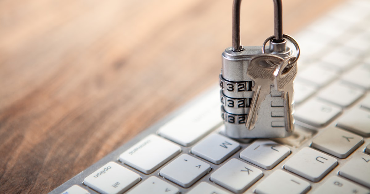 Padlock and keys resting on a computer keyboard.